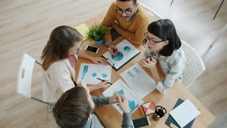group of professionals sitting at a table looking at charts and graphs
